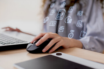 Close up hand of business asian young woman with curly hairstyle holding digital computer mouse and clicking working with computer laptop.Female freelancer using wireless mouse on desk at home