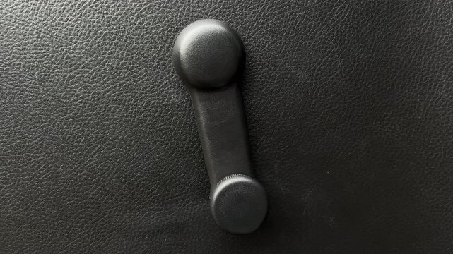 Car manual window crank handle close-up on black interior