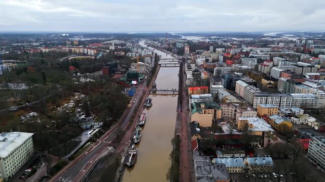 Aerial view flying along the Aurajoki river, cloudy day in Turku city, Finland