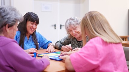 Caregivers and seniors enjoying board game together in nursing home