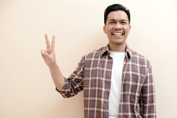 Southeast Asian man wearing flannel shirt showing happy excited expression with giving number 12345 by hand gesture, on white isolated background.