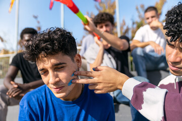 Group of diverse friends expressing team spirit by painting faces to show support during a sporting event in the stands