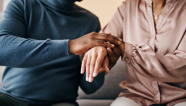 Close up of black man's hands holding woman's hands in a comforting gesture. Concept for emotional support, empathy and relationship guidance