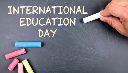 International Education Day Chalkboard Message with Hand and Colorful Chalk Pieces