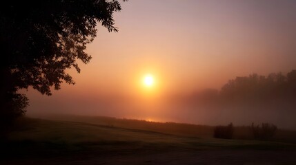 A tranquil sunrise casts a golden glow through dense fog over a serene landscape with mist reflecting the light