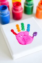 Colorful handprint art project on canvas with paint jars in the background