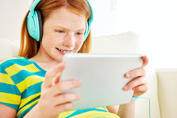 Watching movies the wireless way. Shot of a little girl using a digital tablet at home.