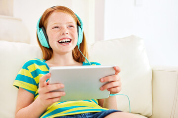 Happy, headphones and child with tablet on sofa in home watching movie, series or show in living room. Smile, digital technology and girl kid streaming film on website for entertainment in house.