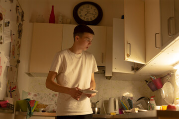 teen standing at kitchen counter cooking and following recipe, novice chef energy with utensils and...