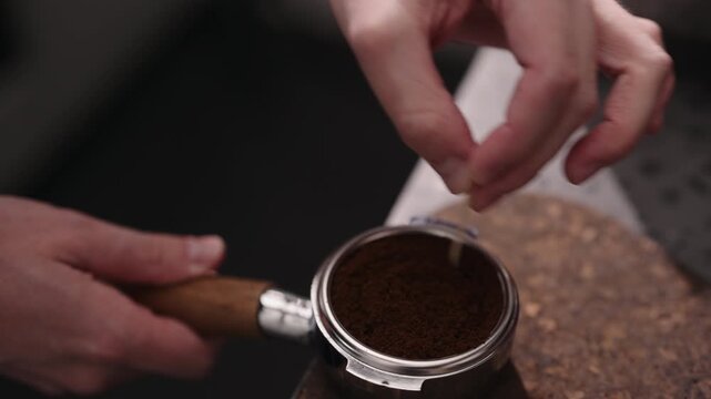 Closeup of man spreading and tamping fresh coffee in pottomless portafilter