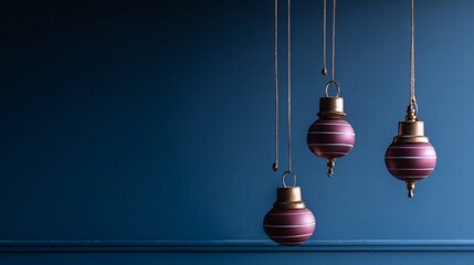 Obraz premium Three hanging ornaments with gold accents against a dark blue background.