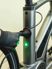 A mechanic in a workshop connects a charging cable to an e-bike frame.
