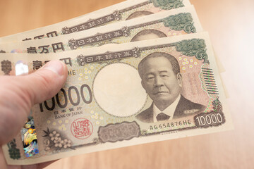 一万円札を手に持つ日本円の現金と資金イメージ