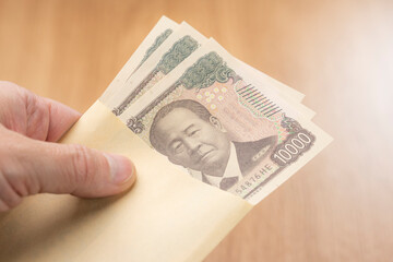 封筒から一万円札を取り出す手元が示す日本円の支払いイメージ