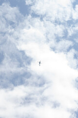 Obraz premium small airplane soaring through cloudy sky, tiny silhouette framed by dramatic cumulus clouds, high-altitude
