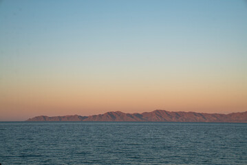 A wide landscape view of a desert island and wide sea at sunset