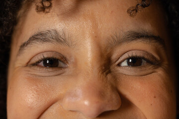 African American woman showcasing fine lines creasing corners of eyes under focused studio lighting
