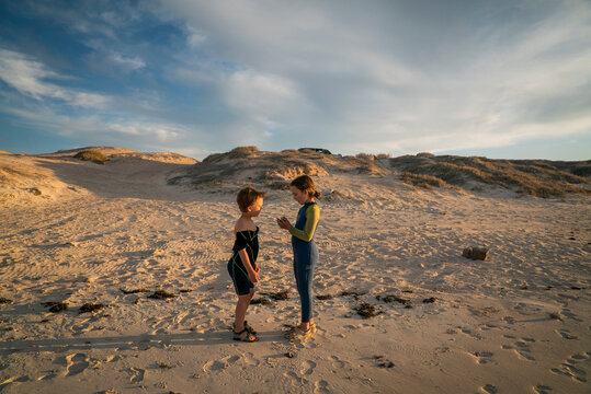 A young boy and young girl look at shells on an empty beach