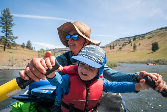 A woman and young boy row a raft on a sunny river.