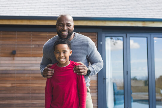 African American father and son standing on wooden deck in backyard smiling showing wristwatch