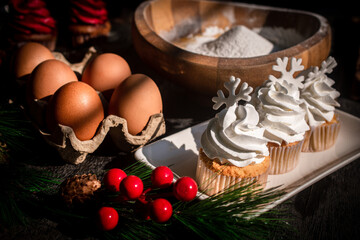 Delicious Christmas cupcakes with snowflakes and festive decorations on a black wooden table.