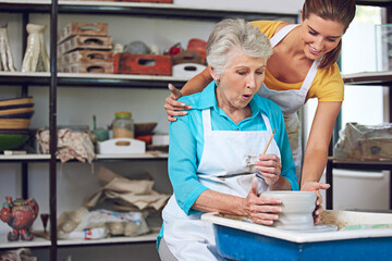 Obraz premium Pottery, lesson or old woman in workshop with help, clay wheel or creative practice in retirement hobby. Art, people or instructor in studio with support, learning or ceramic mold in senior activity.