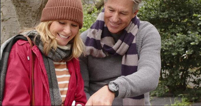Couple spotting notebook, leaning on park bench to review, pointing at idea, writing plans
