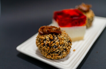 A close-up of a chocolate dessert covered in chopped nuts with a caramel topping, placed on a white plate against a dark background. A strong food macro ideal for confectionery, bakery, and sweet indu