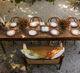 Wooden outdoor table in a garden courtyard set with vintage plates