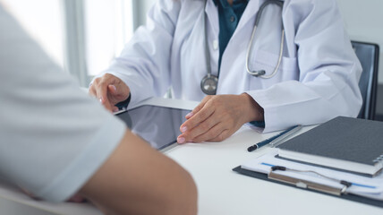 Doctor and patient at medical clinic. Doctor using digital tablet for giving result or health report and advice to the patient on health checkup. closeup