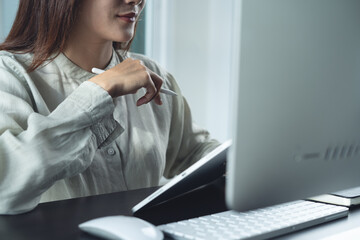 Closeup, asian business woman using digital tablet and working on desktop computer at office. Young smart businesswoman have a discussion joining online meeting with colleagues, remote work