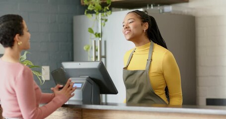 Female barista greeting customer at cafe counter after placing phone at QR code guiding payment