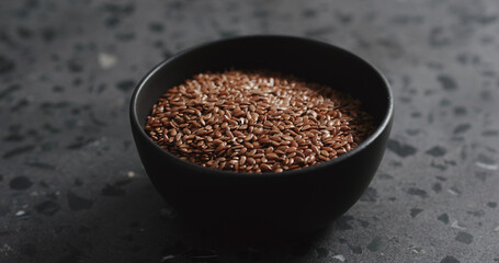 flaxseed in black bowl on terrazzo countertop with copy space