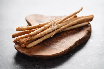 bunch of handmade wholegrain grissini tied with rope on olive board