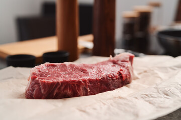 Raw new york sirloin steak on parchment paper warming up before cooking