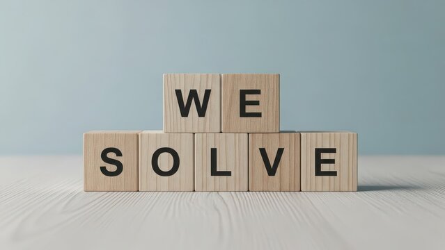 Wooden scrabble tiles spelling out we solve arranged creatively on a light surface against a soft blue background