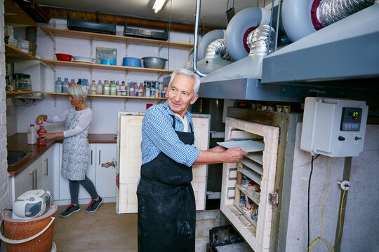 Ceramic, process and old people in workshop with oven, skills or creative hobby in retirement. Preparation, art and man in studio with kiln, production or sculpture craft in senior activity.