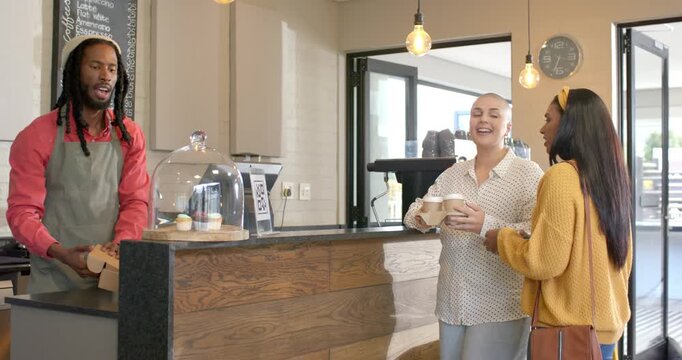 African American barista serving at counter friends holding cups lifting dome grabbing pastry box
