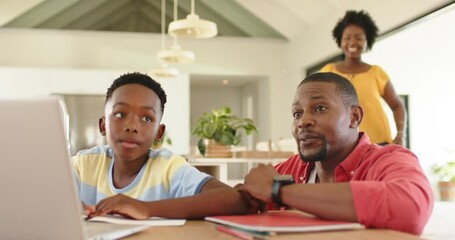 African American family guiding son typing on laptop after homework prompt, mother joining at home - Powered by Adobe