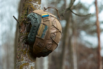Obraz premium STAND WITH UKRAINE. Military helmet on tree brunch. helmet with a blue-yellow flag and the inscription Ukraine