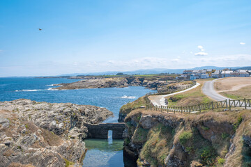 path along the coast in the small fishing village of Rinlo, Lugo, Spain, with the old natural fish farm in the foreground
