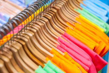 Colorful shirts hang on hangers in a clothing store, ready for sale.