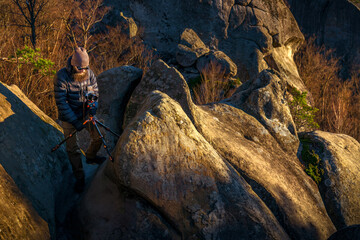 Bearded outdoor photographer using medium-format camera and pro tripod to shoot sunrise in mountains