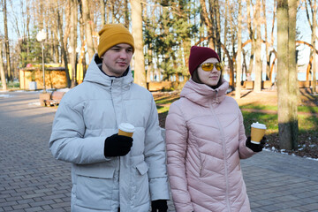 Young couple walking in a park drinking coffee