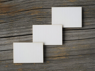 Three blank white business cards elegantly arranged on a rustic wooden background, ready for your custom design and branding needs
