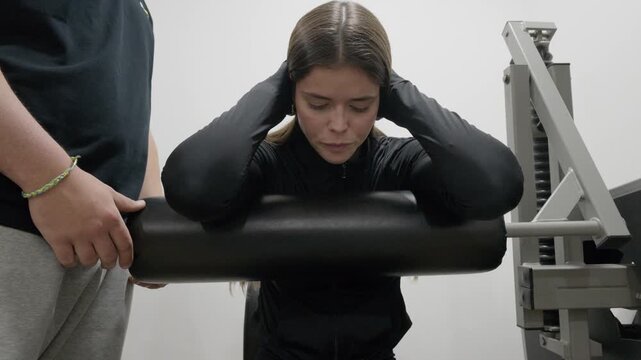 Determined woman performing squats on a machine at the gym