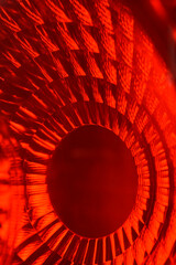 A vibrant close-up, abstract macro shot captures a bright red, textured light with a prominent central dark circle