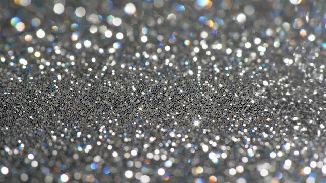 Macro view of silver glitter particles slowly vibrating and sparkling in bright light creating a mesmerizing glamorous texture glamorous texture, surface, celebration