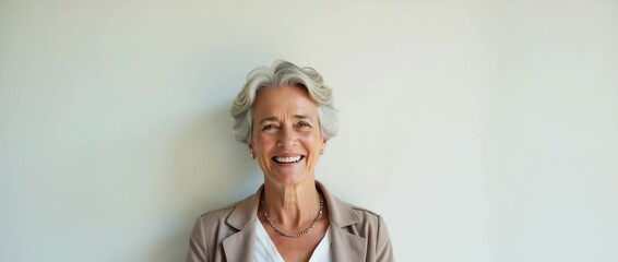 Elderly woman smiles warmly against a minimalist background, as the camera slowly pans, capturing gentle ambient lighting in a serene, cinematic style, perfect for wellness and retirement themes.