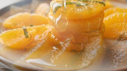 Vibrant citrus segments, glistening on a plate, are drizzled with golden syrup. Fresh green herbs garnish this appetizing close-up. Perfect for food advertising, recipes, or healthy dessert promotions